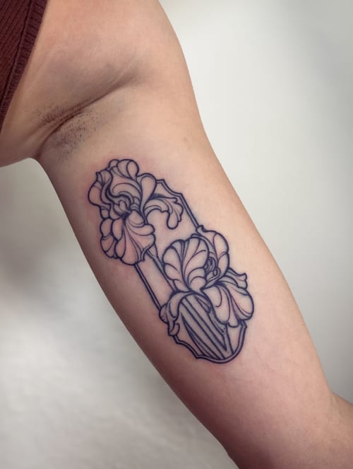 A delicate black linework floral design on the inner arm, featuring intricate flower details — by Melanie Benoit, los angeles