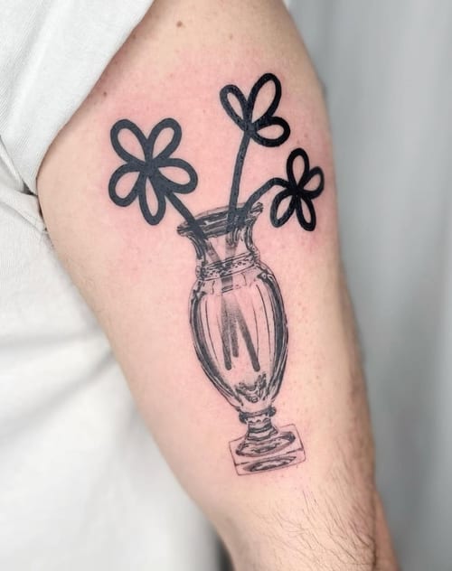 A minimalist black and grey tattoo of a vase with simple linework flowers on the upper arm — by Level tattoo, los angeles