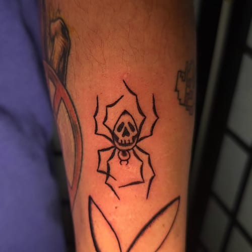 A bold blackwork tattoo of a skull spider on the forearm, featuring minimalist linework — by Miguel ANGELO, los angeles