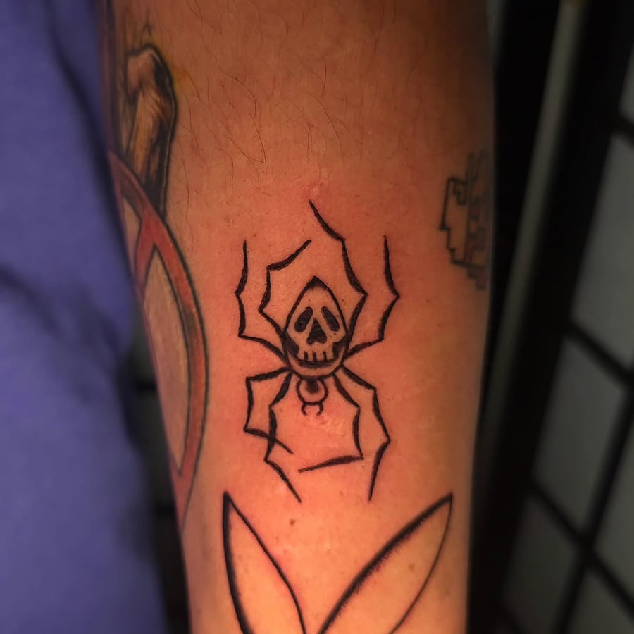 A bold blackwork tattoo of a skull spider on the forearm, featuring minimalist linework — by Miguel ANGELO, los angeles