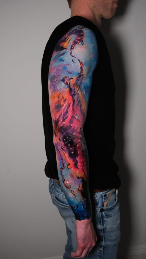 A vibrant watercolor full sleeve tattoo depicting a colorful cosmic scene with swirling nebulae and stars — by Nik Lucas, los angeles