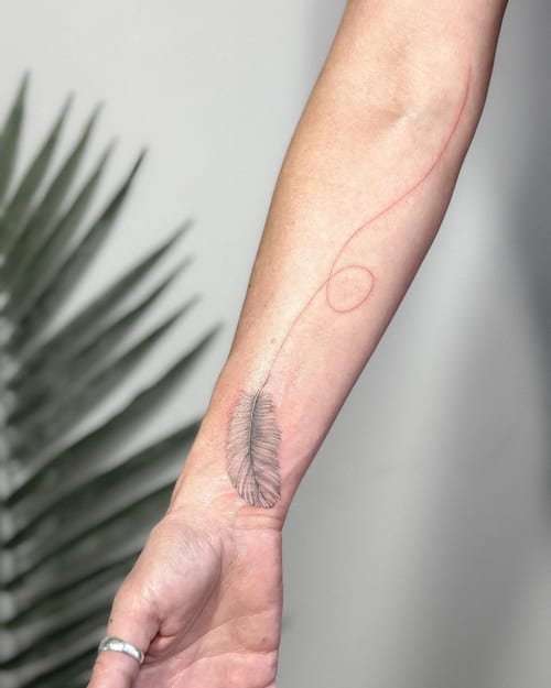 A delicate fine line feather tattoo on the forearm with a minimalist design and subtle shading — by Melanie Benoit, los angeles