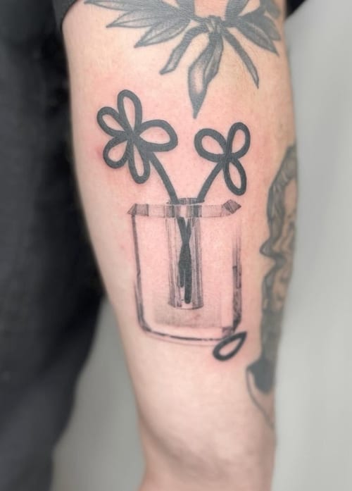A minimalist blackwork tattoo of two simple flowers in a vase on the forearm, featuring bold outlines and a clean design — by Level tattoo, los angeles