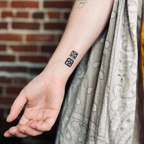 A minimalist blackwork tattoo of geometric tile designs on the forearm, featuring clean lines and simple shapes — by Dylan Aiello, los angeles