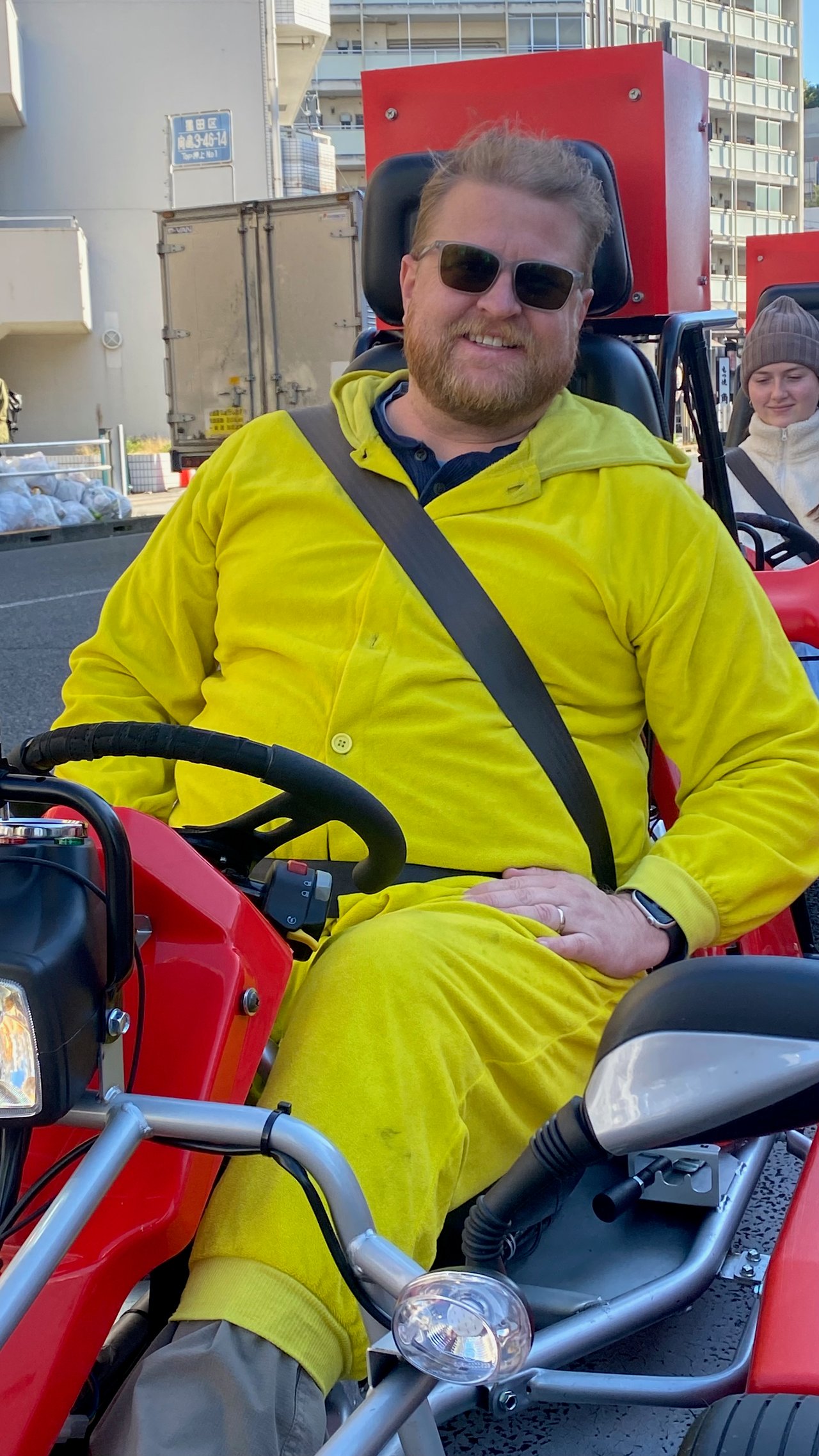 Adam sitting in a go kart wearing a Pikachu costume on a Tokyo street