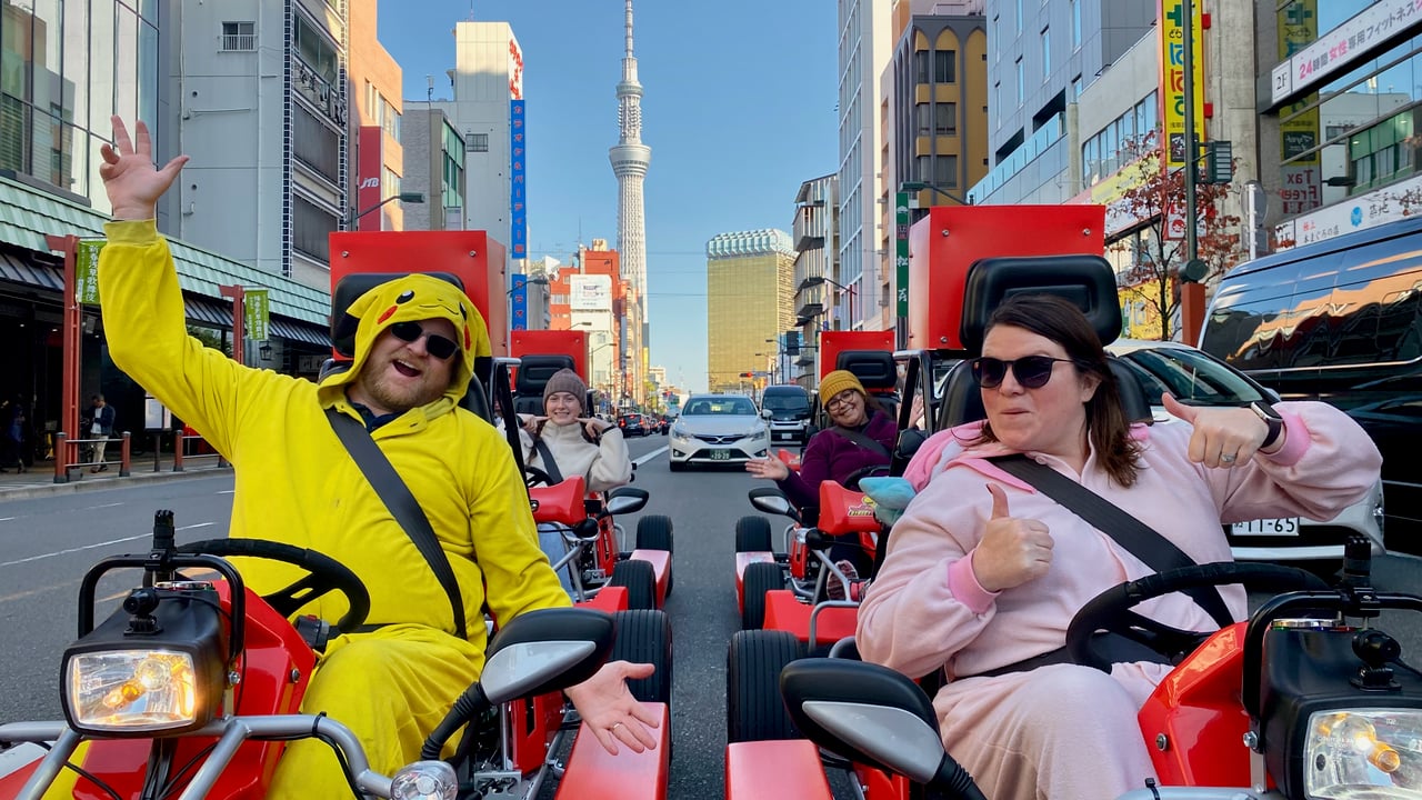 Adam and Lindsay riding side by side in go karts through Tokyo streets