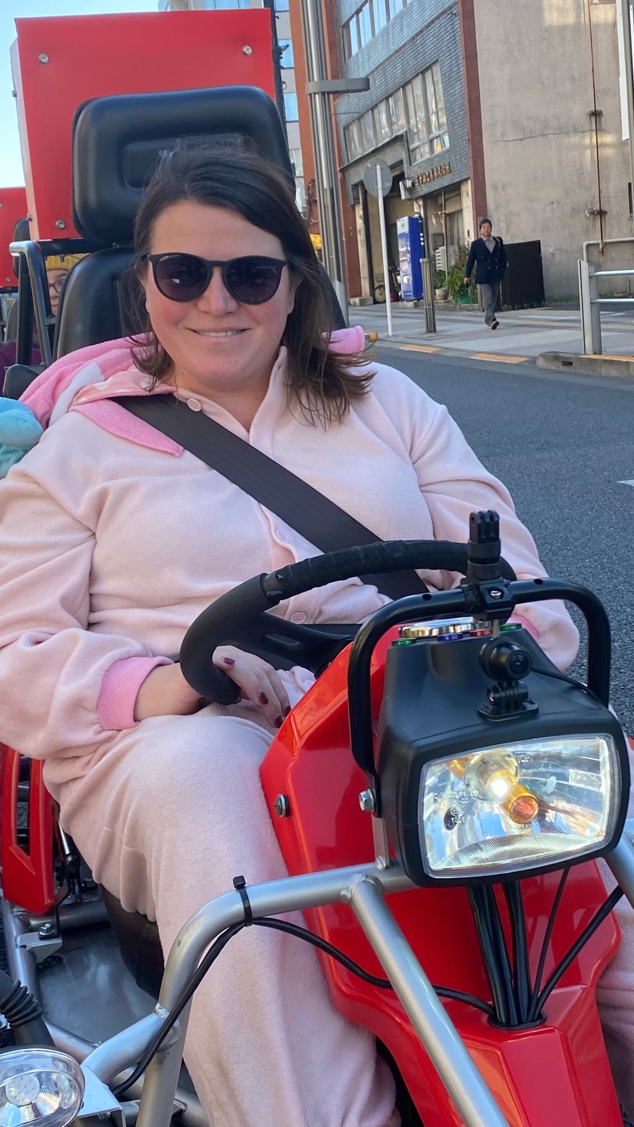 Lindsay sitting in a go kart wearing an Eevee costume on a Tokyo street