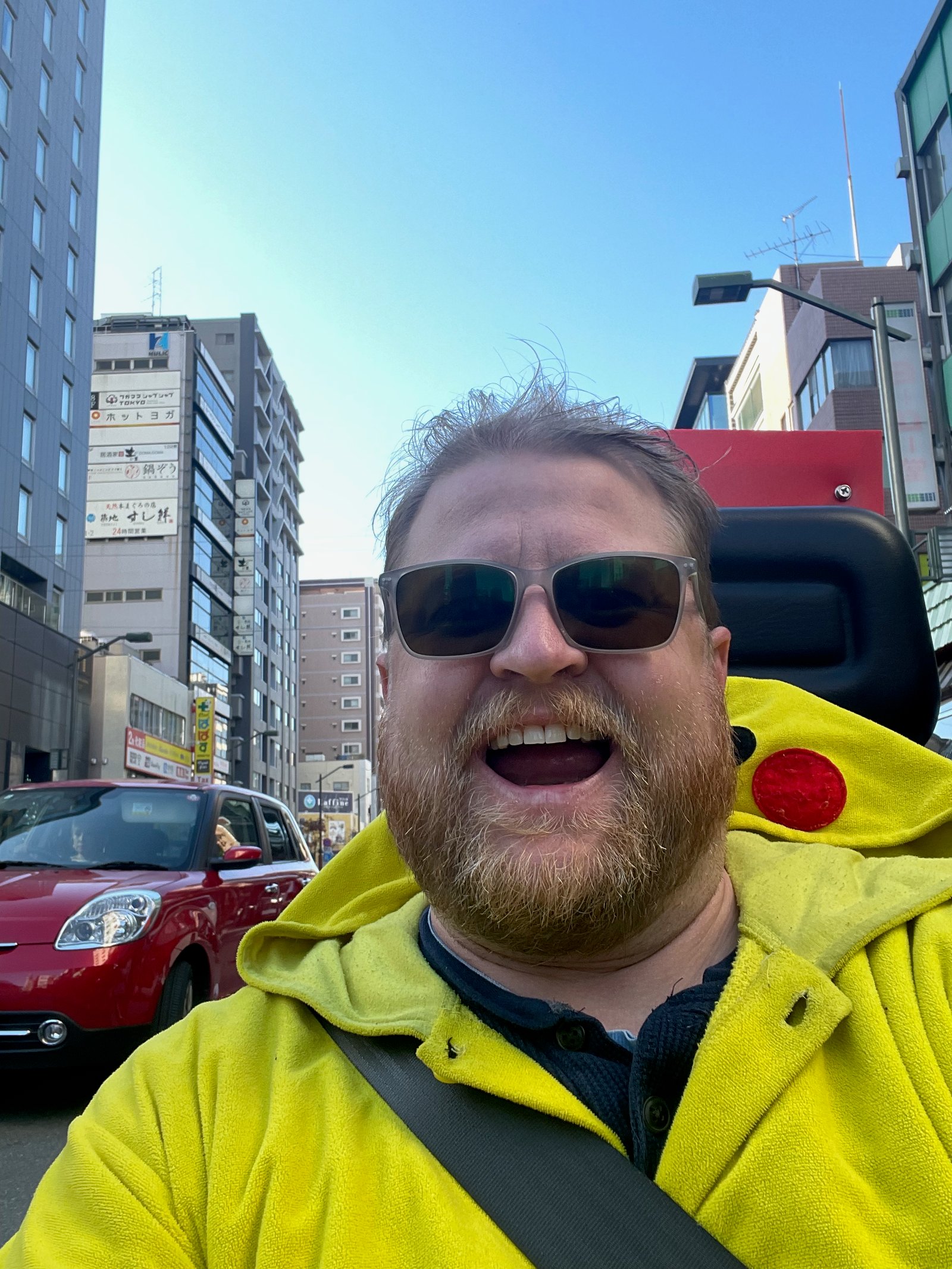 Adam cheering while riding a go-kart dressed as Pikachu through Tokyo streets
