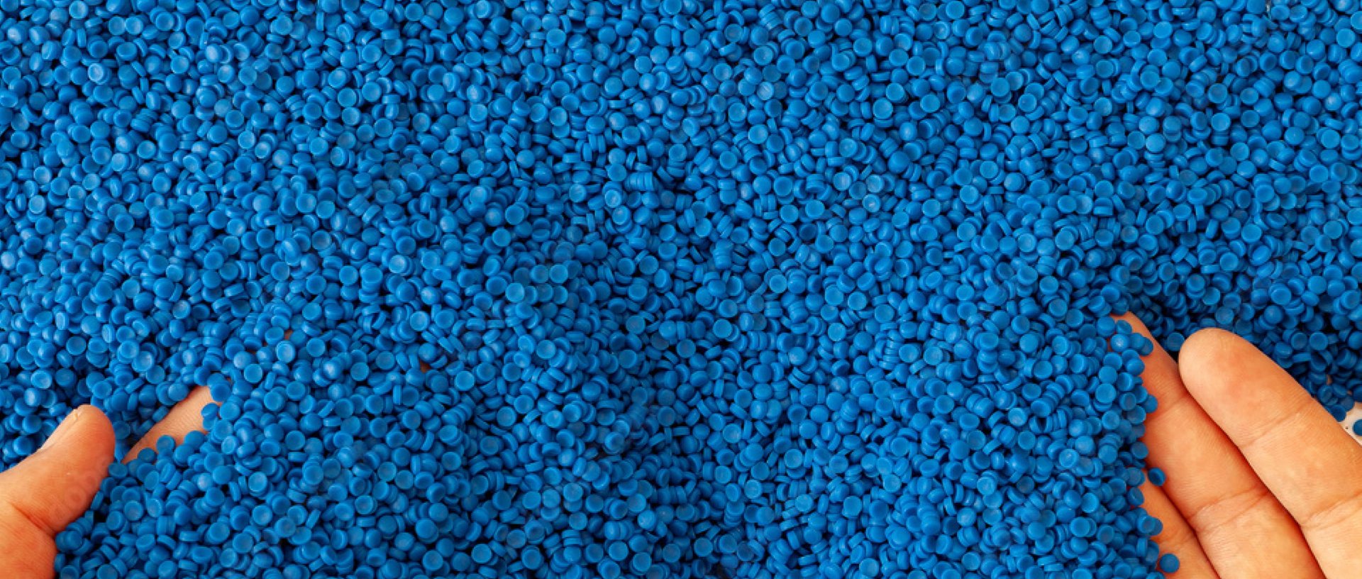 Close-up of blue plastic polymer granules. Hand hold. Polymer pellets. Compound polymer.