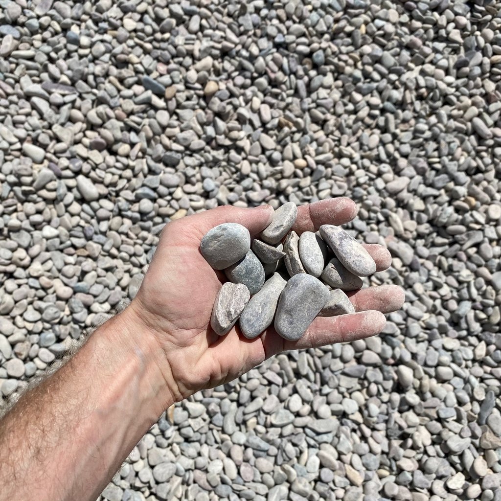 Image of Missoula round river rock taken from above with a hand for scale.