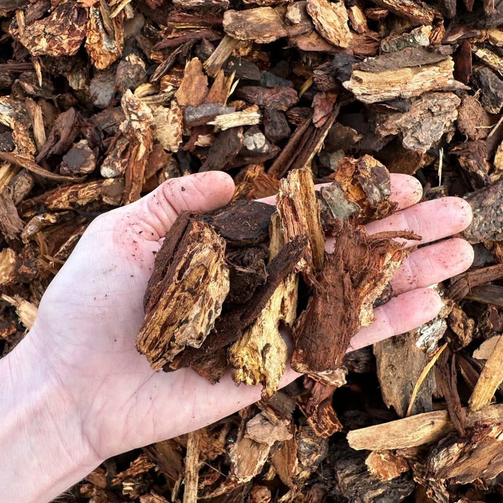 Overhead photo of Missoula Nugget Fir Bark for delivery with a hand for scale.