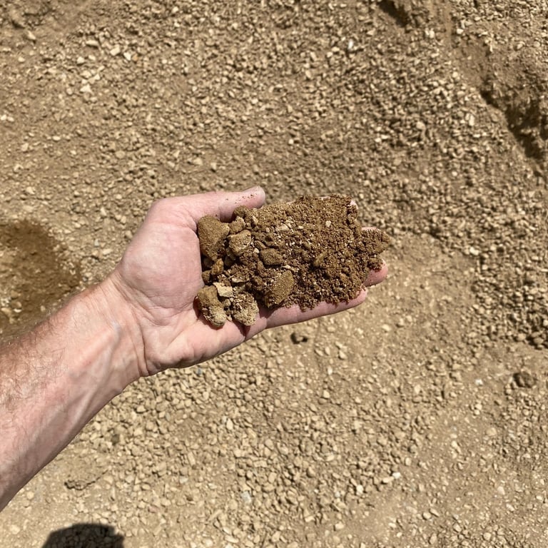 Image showing the texture of road base compaction gravel with a hand for scale.