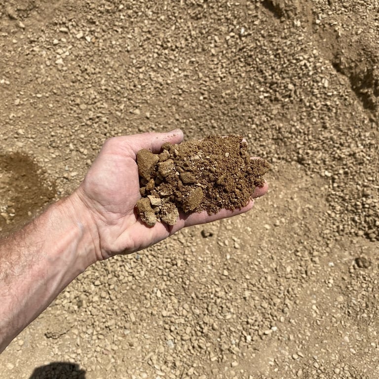 Image showing the texture of road base compaction gravel with a hand for scale.