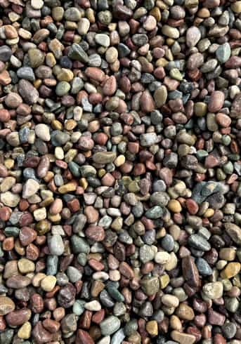 Overhead image that shows the texture of a gray, purple, yellow and reddish toned round river rocks that have been sorted by a similar size.