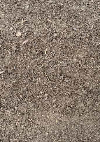 Overhead image that shows the texture of a dark brown organic garden soil.