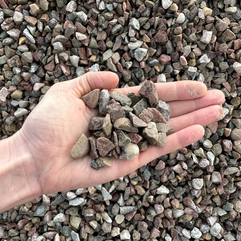 Overhead photo of wet Missoula Crushed River Rock in the 0.75 inch size, ready for delivery. A hand is included for scale.