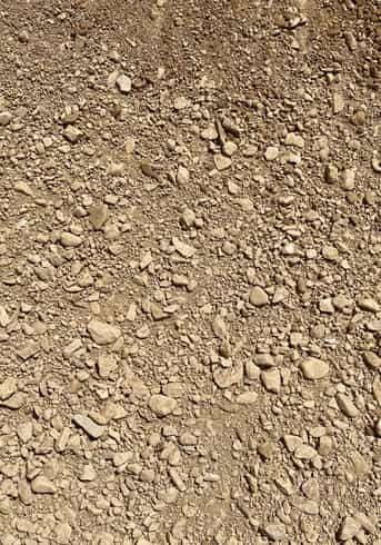 Overhead image that shows the texture of a yellowish gravel consisting of smaller stones down to sifted fines for compaction purposes.