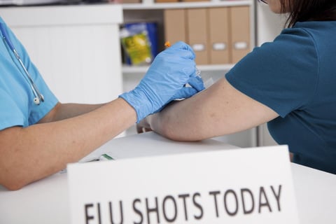 A woman receiving a flu shot in the arm.