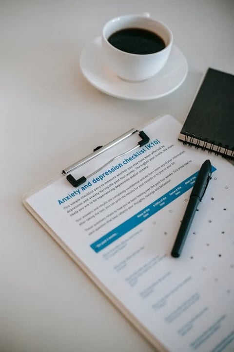 A mental health checklist on a clipboard with a pen and coffee cup.