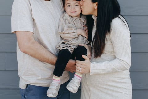 A couple kissing their child.