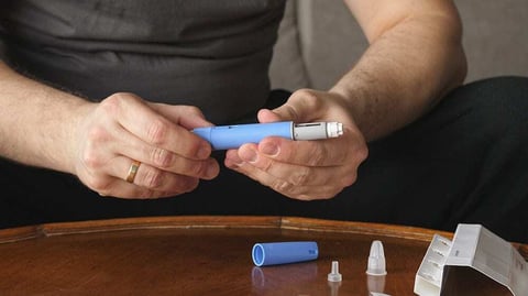 Man preparing an Ozempic injection device for use.