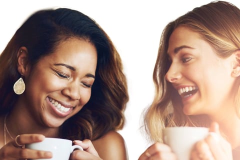 Two women drinking tea together and laughing.