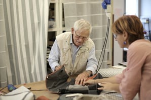 Elderly man with a middle aged female doctor with a blood pressure sleeve laid on the table between them.