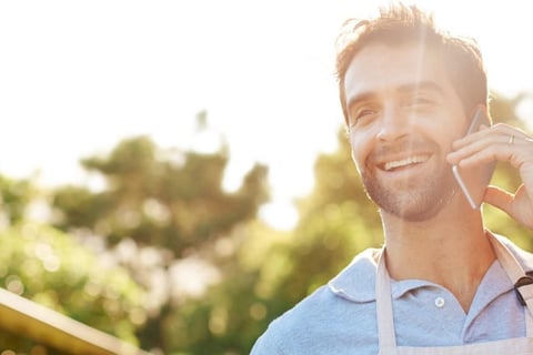 A smiling man speaking on his mobile phone in the sun.