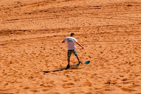 Ride a sandboard over the desert dunes