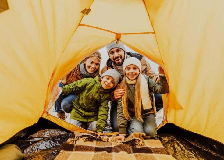 Family bonding outdoors: A joyful moment captured with a yellow tent, creating lasting memories in the embrace of nature.