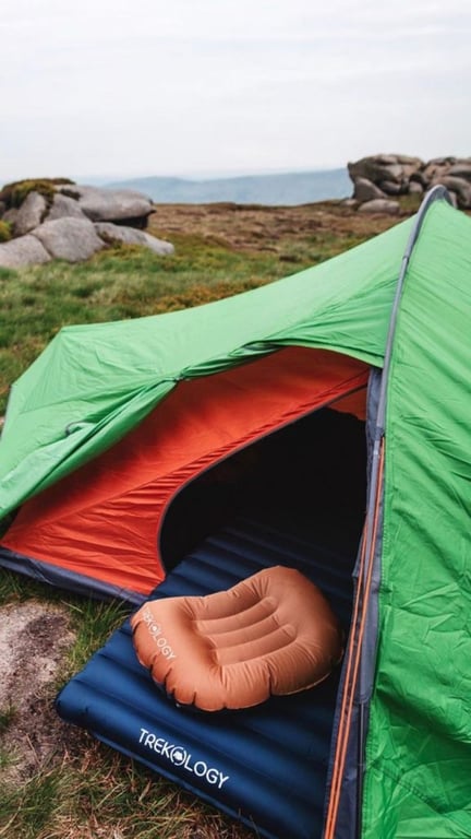Cozy retreat in a green tent with vibrant orange pillows, offering a perfect blend of comfort and nature for a relaxing outdoor getaway