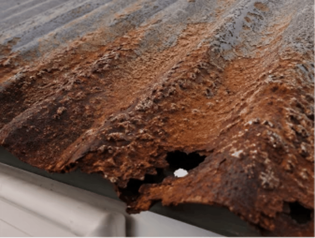 A perforation through a heavily rusted corrugated metal roof