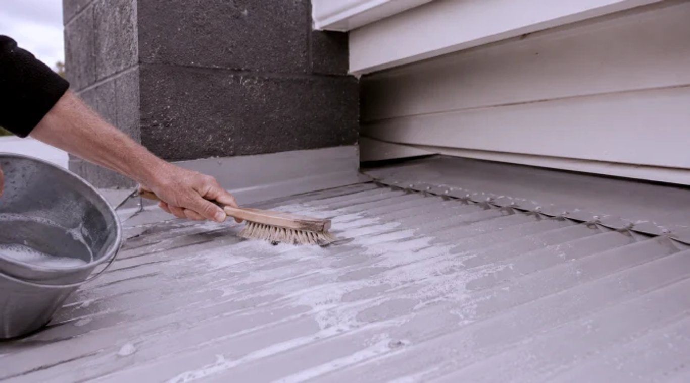 Metal roof being cleaned by hand with a soft-bristled brush