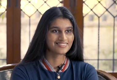 A young woman sitting in a chair smiling.