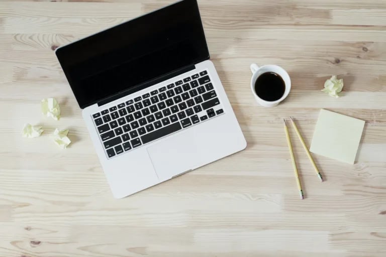 A laptop on a wooden table with a cup of coffee and a notepad, perfect for studying STEM Education or IIT JEE Mains.