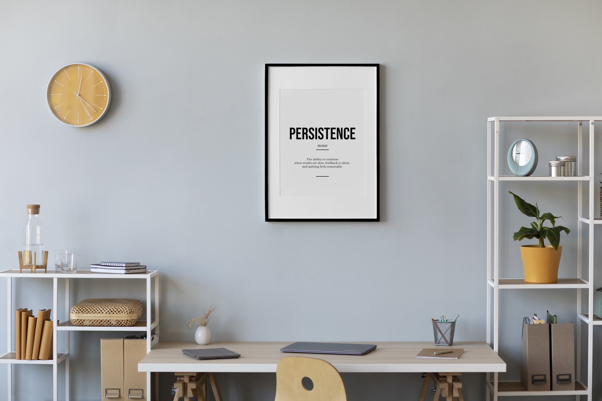 A Motivarr definition poster in a thin black frame on a clean desk in a minimal dorm room workspace