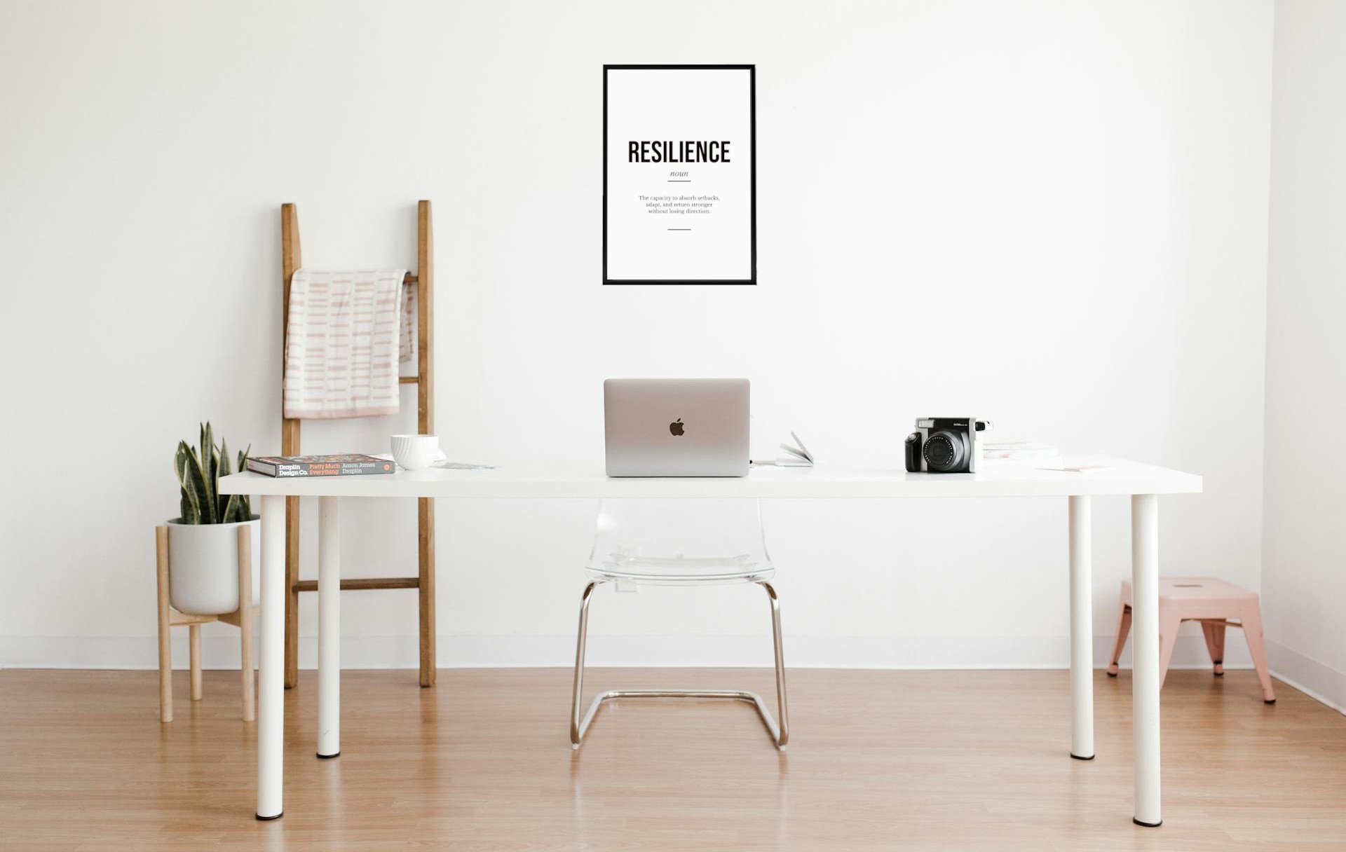 The Motivarr Resilience definition poster in a thin black frame on a clean wooden desk above a minimal workspace