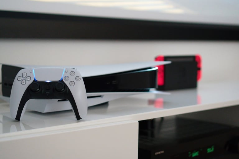 PS5 von vorne vor einer Beamerleinwand auf einem weißen Lowboard