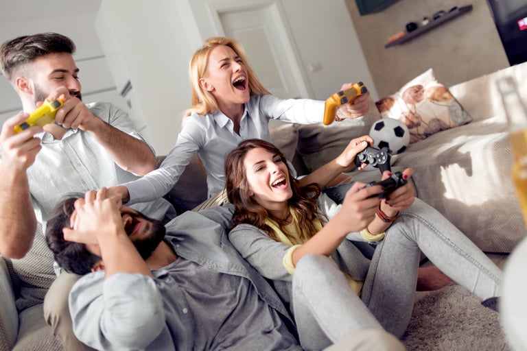 Vier Freunde spielen mit einer Videospielkosnole auf einer Couch