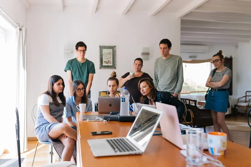 employees huddled around a laptop