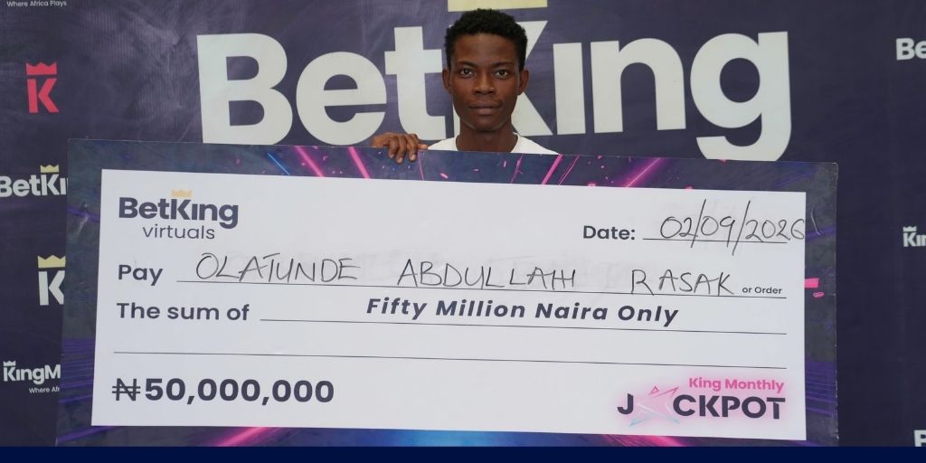 An image of Olatunde Abdullah, BetKing's Virtuals Jackpot winner beaming while holding his prize cheque money