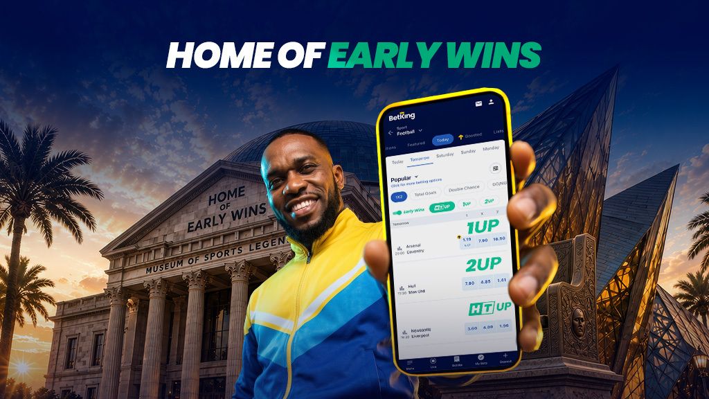 JayJay Okocha holding up a phone with market options prominently displayed on the screen