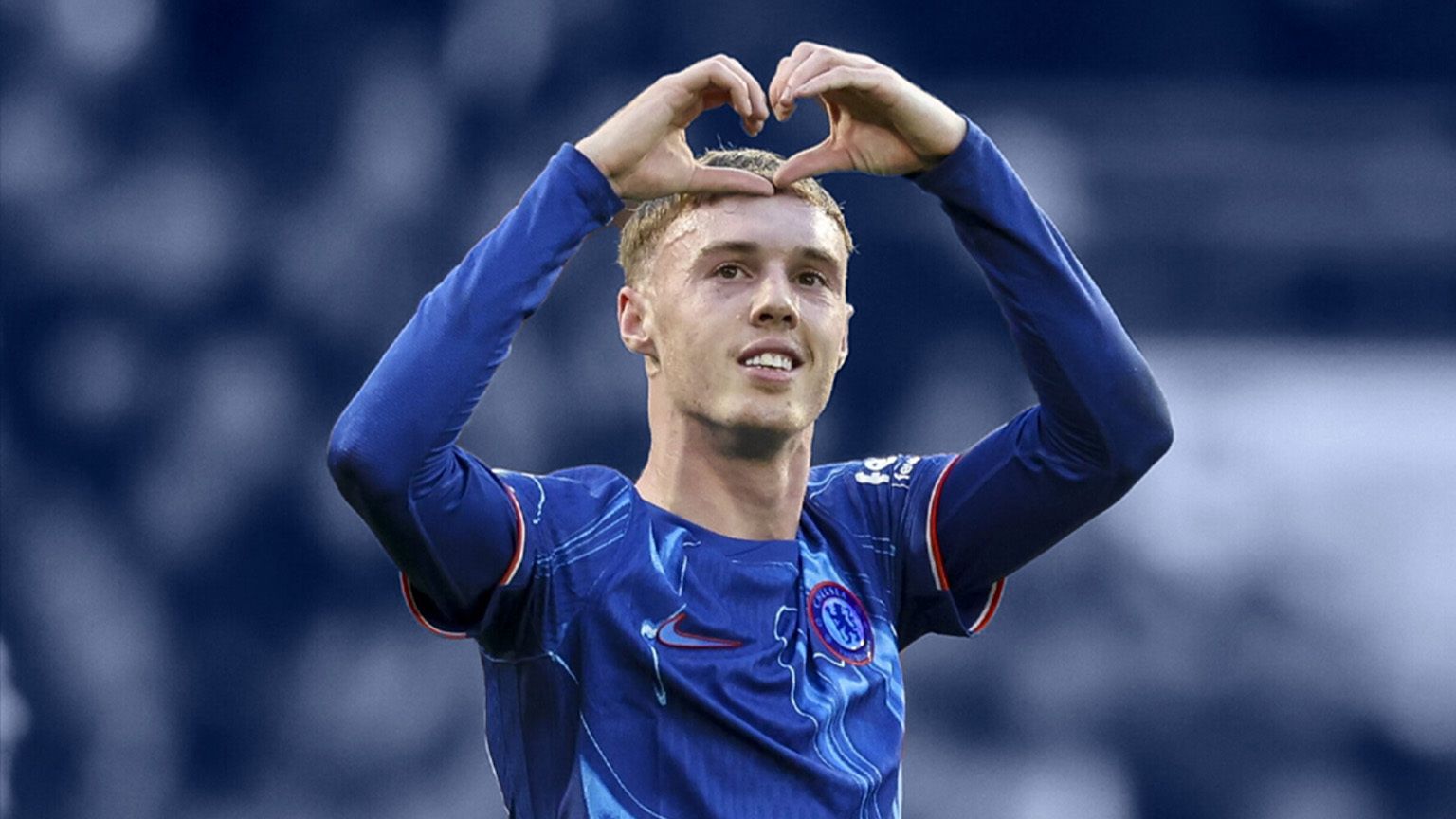 Cole Palmer, wearing a Blue Chelsea jersey and making a "heart" shape with his hands/fingers