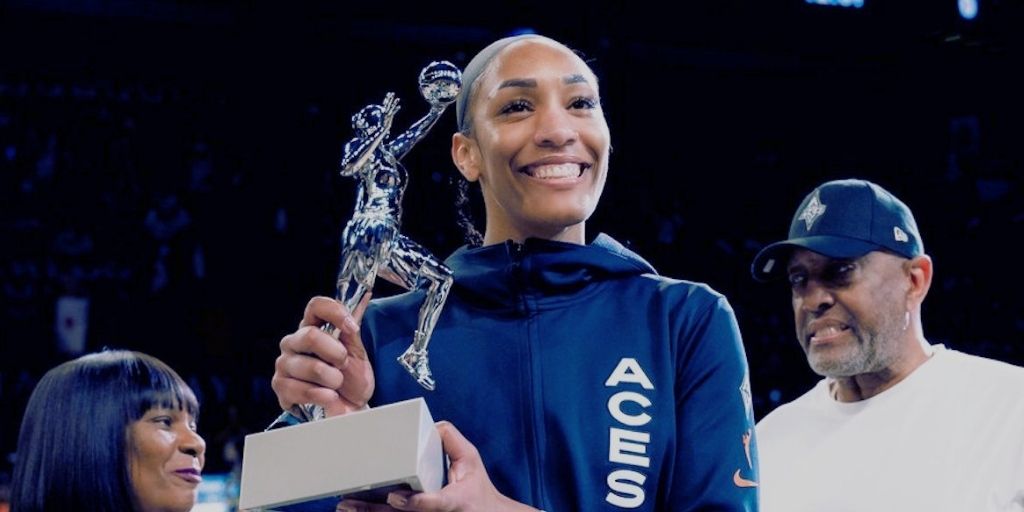 A’ja Wilson of the Las Vegas Aces smiles while holding a basketball trophy during an on-court presentation.