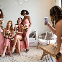Bridesmaids in pink dresses take photos for a wedding guest book using a phone. Perfect for collecting wedding photos.