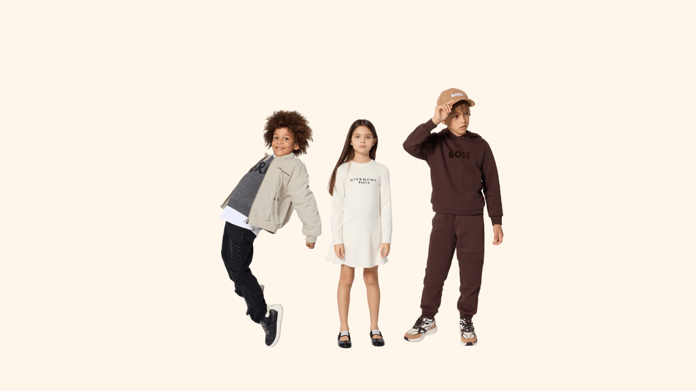 Three children in designer knitwear — a beige bomber, a Givenchy dress, and a Boss outfit — on a soft ivory ground