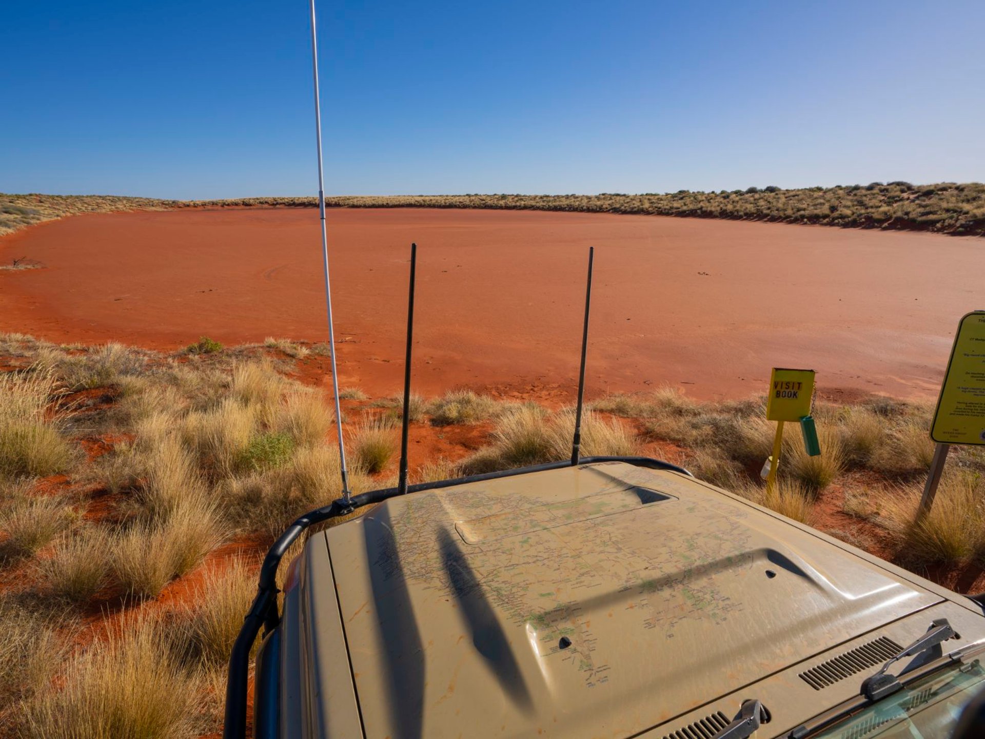 Touring 4WD parked at a red claypan in the outback, UHF antennas up