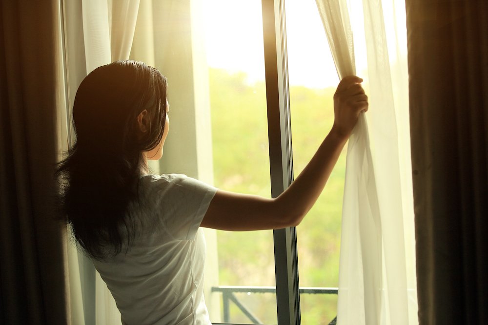 chinese woman opening the curtains