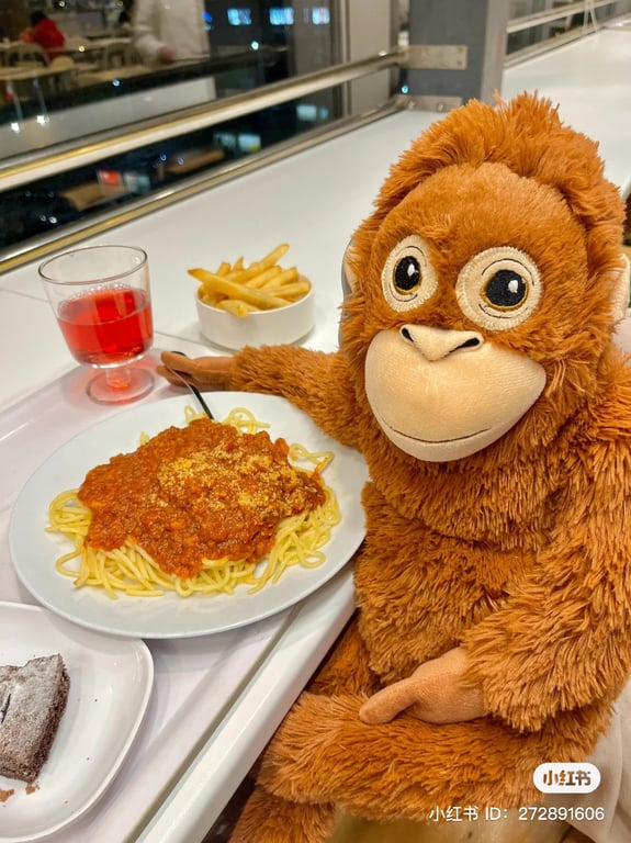 a stuffed monkey eating a plate of spaghetti