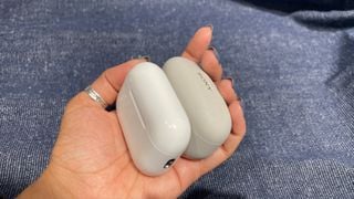 Carcase de încărcare Sony WF-1000XM5 și Apple AirPods Pro 2 ținute în mână
